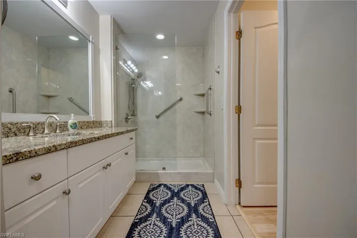 Bathroom featuring a tile shower, tile patterned flooring, and vanity