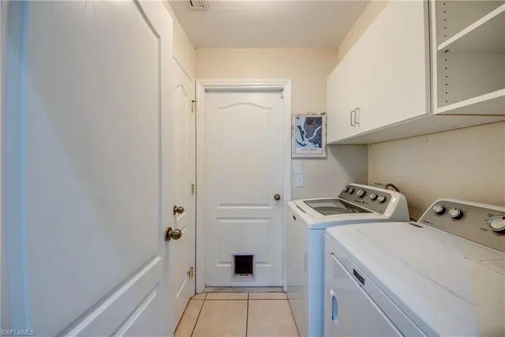 Laundry room with cabinets, independent washer and dryer, and light tile patterned floors