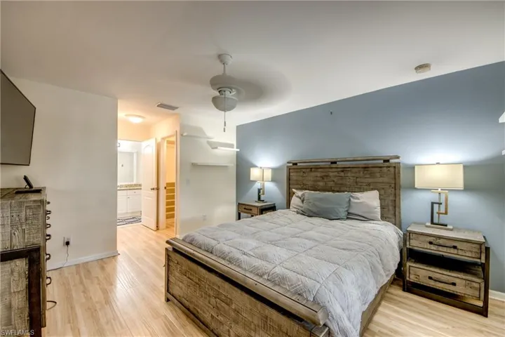 Bedroom with light hardwood / wood-style floors, ensuite bath, and ceiling fan