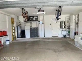 Garage with water heater, a garage door opener, and white fridge