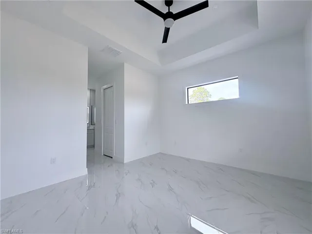 Spare room with ceiling fan and a tray ceiling