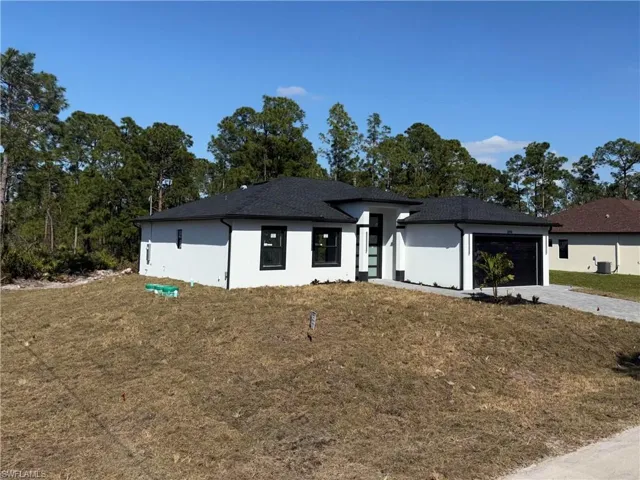 View of front of property featuring a front yard, concrete driveway, and an attached garage