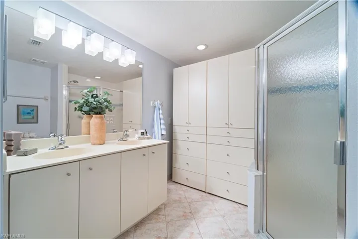 Bathroom featuring a shower stall, double vanity, light tile patterned floors, and recessed lighting