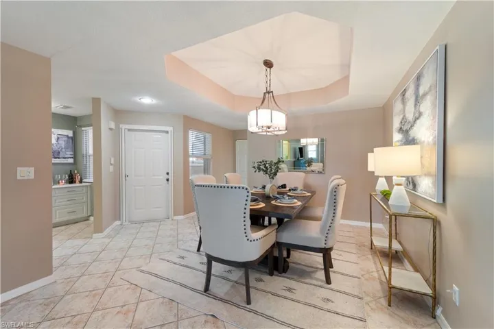 Dining room with a raised ceiling, light tile patterned floors, and a chandelier