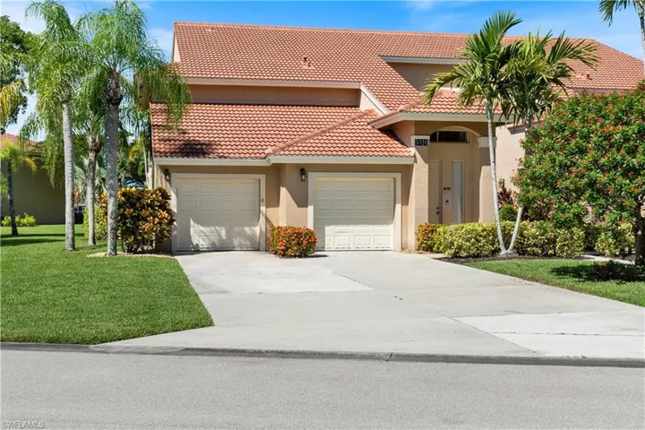 Mediterranean / spanish home featuring driveway, a tiled roof, an attached garage, stucco siding, and a front lawn