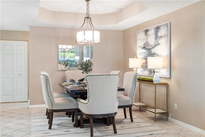 Dining area with a raised ceiling, a chandelier, and light tile patterned floors