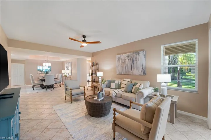 Living room with ceiling fan and light tile patterned flooring
