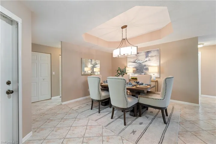 Dining space featuring a tray ceiling, light tile patterned flooring, and a chandelier
