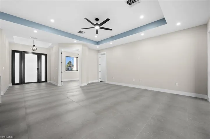 Unfurnished living room with a tray ceiling and ceiling fan