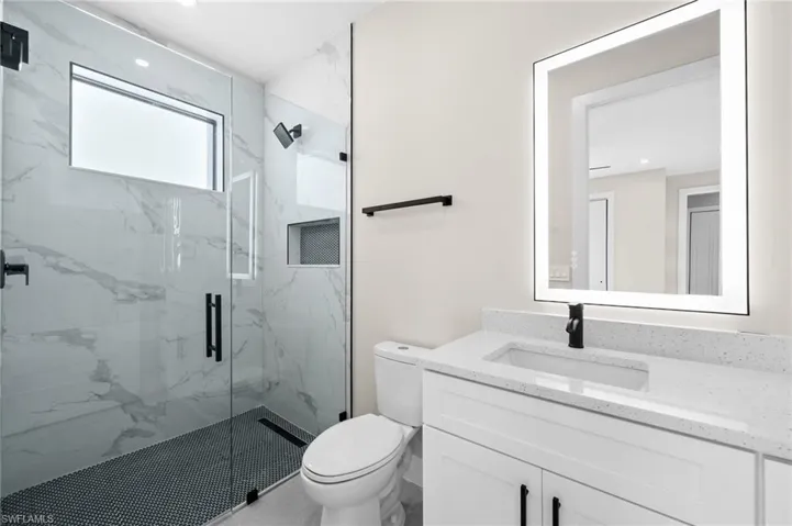 Bathroom with vanity, toilet, and an enclosed shower