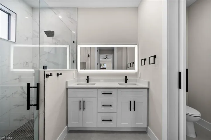 Bathroom with vanity, toilet, an enclosed shower, and ceiling fan