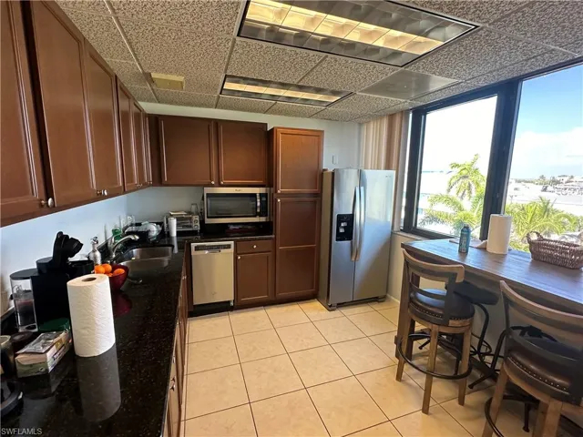 Kitchen featuring a drop ceiling, sink, light tile patterned flooring, and appliances with stainless steel finishes