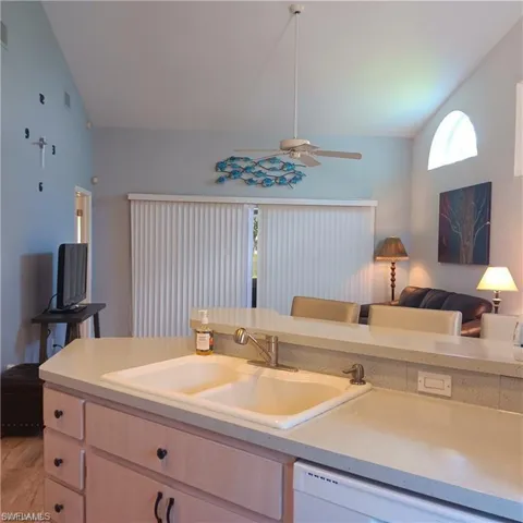 Kitchen with ceiling fan, light hardwood / wood-style flooring, vaulted ceiling, dishwasher, and sink