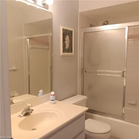 Full bathroom featuring enclosed tub / shower combo, vanity, and toilet