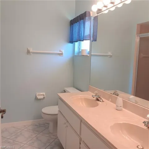 Bathroom featuring a shower with door, toilet, tile patterned flooring, and vanity