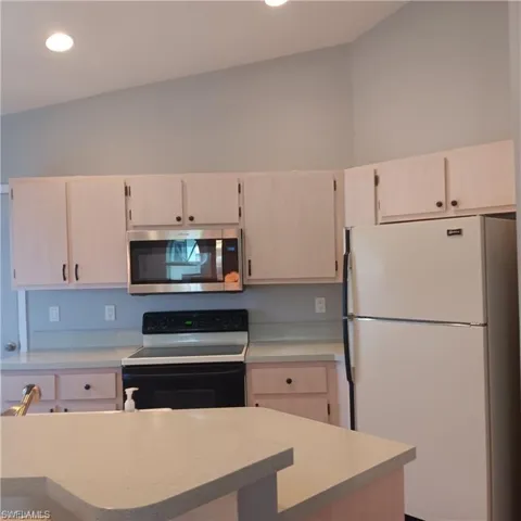 Kitchen featuring vaulted ceiling and white appliances
