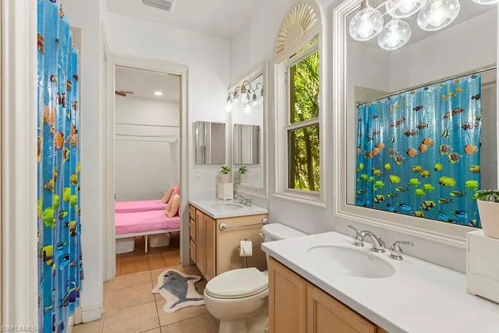 Ensuite bathroom featuring vanity, a shower with curtain, and light tile patterned floors