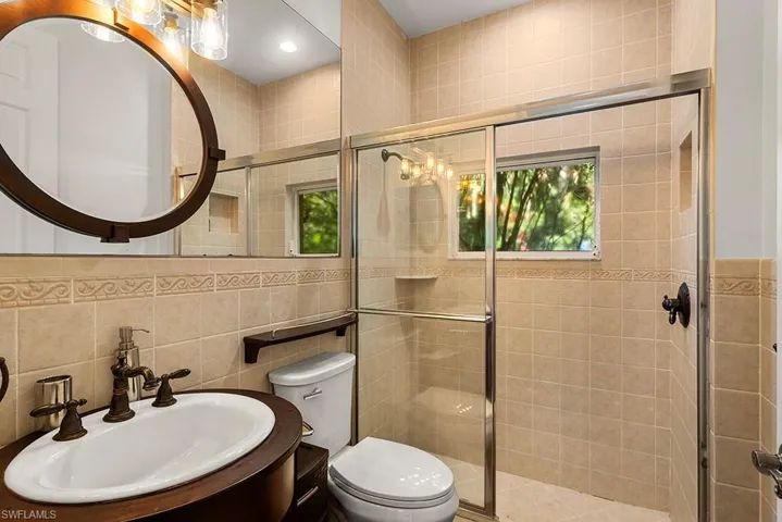 Bathroom featuring tile walls, vanity, a shower stall, recessed lighting, and decorative backsplash