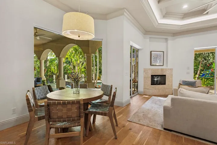 Dining area with a high end fireplace, plenty of natural light, wood-type flooring, crown molding, and a raised ceiling