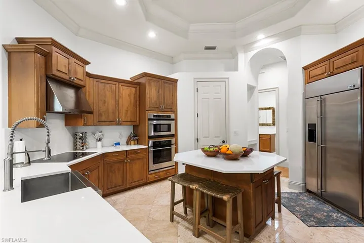 Kitchen featuring stainless steel appliances, a breakfast bar, ornamental molding, a tray ceiling, and wood finish cabinets