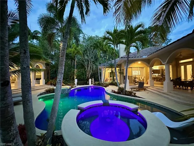 Pool at dusk with a patio and a pool with connected hot tub