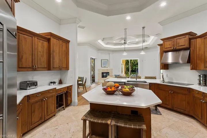 Kitchen featuring ceiling fan, a tray ceiling, a center island, stainless steel built in refrigerator, and pendant lighting