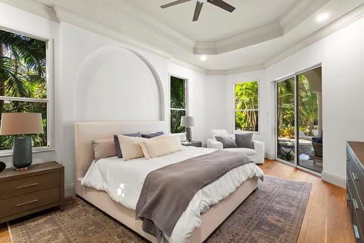 Bedroom featuring light wood-type flooring, access to exterior, a raised ceiling, ceiling fan, and ornamental molding