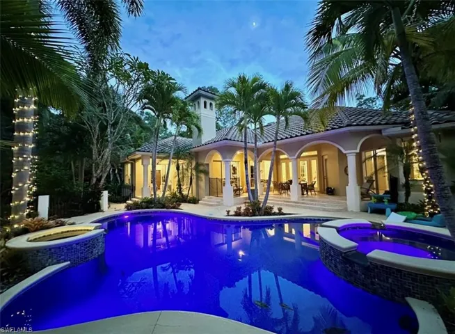 Rear view of property with a pool with connected hot tub, a patio, a tiled roof, and stucco siding