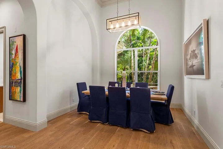 Dining room with wood finished floors, arched walkways, and a high ceiling