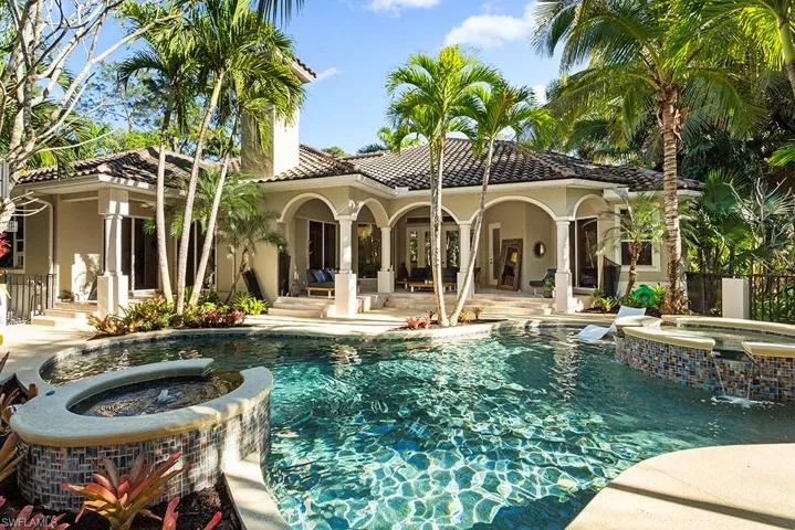 Rear view of property featuring a pool with connected hot tub, a patio, stucco siding, and a tiled roof