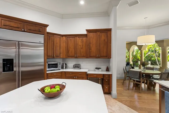 Kitchen with stainless steel built in fridge, crown molding, light wood finished floors, and pendant lighting