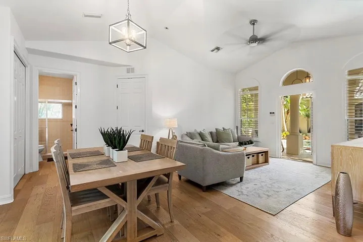 Dining space featuring light wood-style flooring, ceiling fan, a chandelier, and a high ceiling