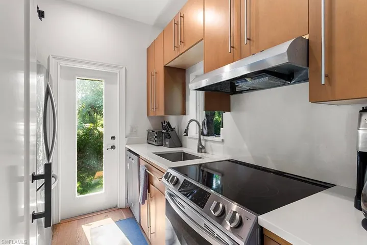 Kitchen with stainless steel electric stove, light stone countertops, wood finish cabinetry, and plenty of natural light