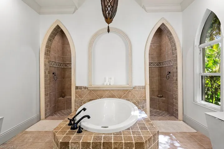 Bathroom with a bath, a walk in shower, ornamental molding, and light tile patterned flooring