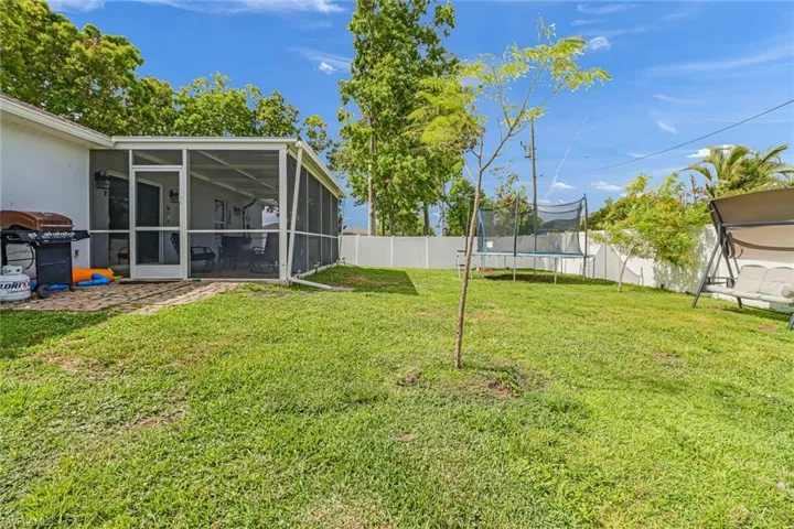 View of yard with a trampoline and a sunroom