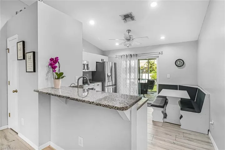 Kitchen featuring light hardwood / wood-style floors, kitchen peninsula, stainless steel appliances, ceiling fan, and white cabinets