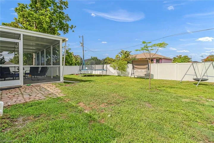 View of yard featuring a patio, a sunroom, and a trampoline