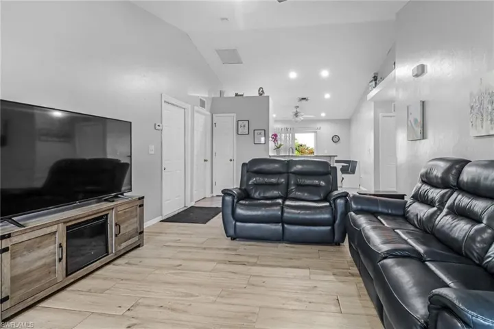 Living room featuring lofted ceiling, light wood-type flooring, and ceiling fan