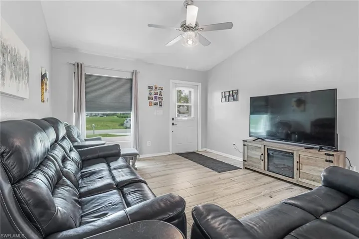 Living room with vaulted ceiling, ceiling fan, and light wood-type flooring