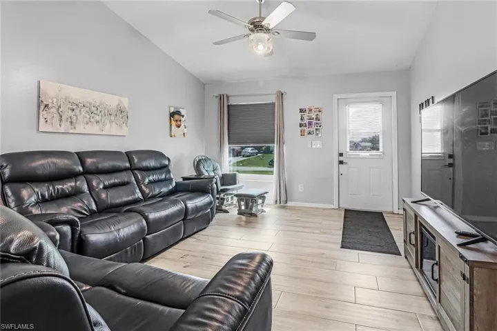 Living room featuring ceiling fan, vaulted ceiling, and light hardwood / wood-style flooring