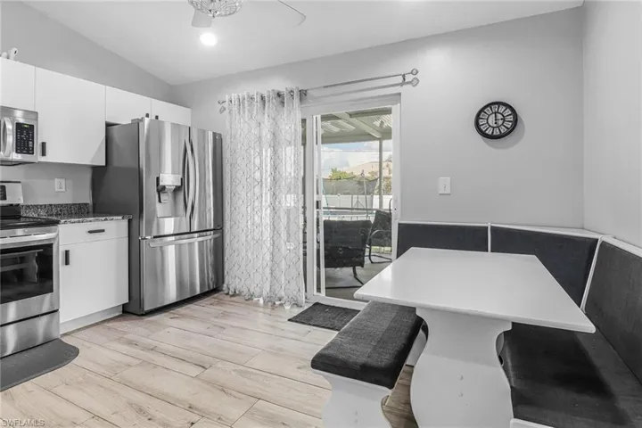 Kitchen featuring stainless steel appliances, white cabinets, ceiling fan, and light wood-type flooring