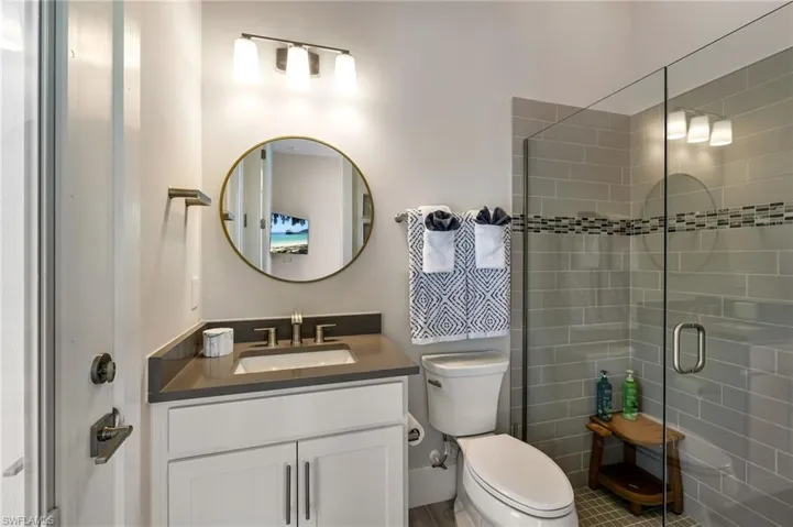 Bathroom with a shower with door, vanity, tile patterned flooring, and toilet