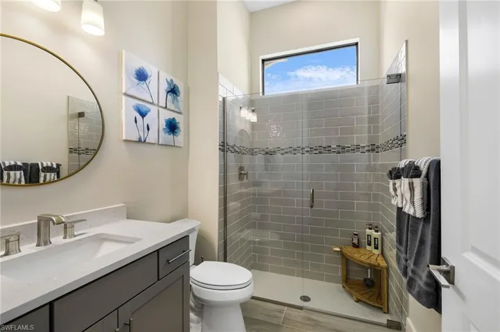 Bathroom with toilet, tile patterned floors, vanity, and a shower with shower door