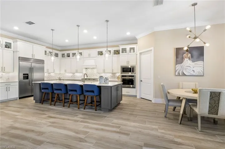 Kitchen with backsplash, pendant lighting, a center island with sink, and built in appliances