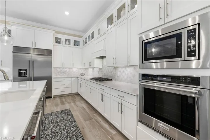 Kitchen featuring built in appliances, sink, white cabinets, light hardwood / wood-style flooring, and decorative backsplash