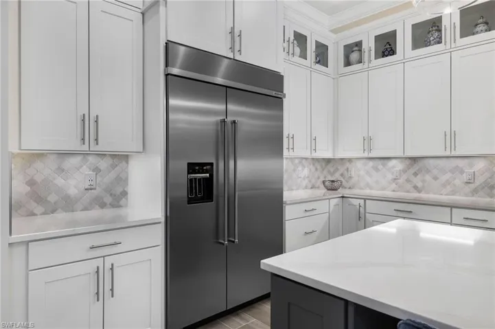 Kitchen featuring backsplash, white cabinets, and stainless steel built in fridge