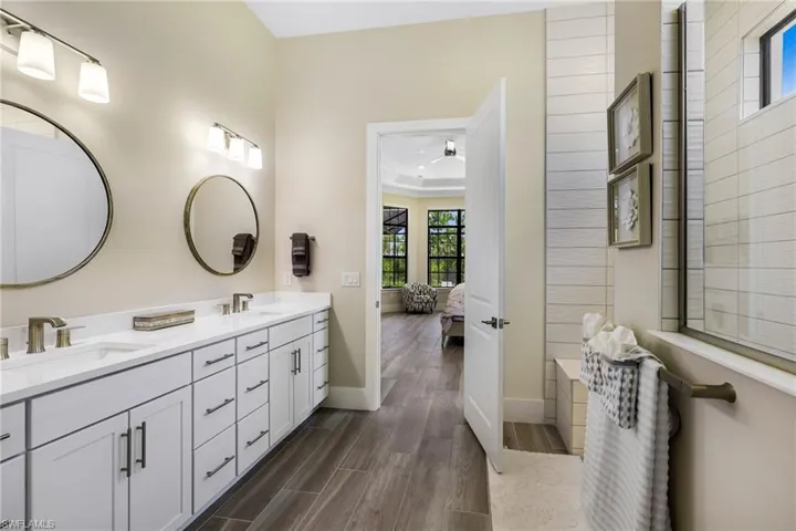 Bathroom featuring ceiling fan, dual bowl vanity, wood-type flooring, and crown molding