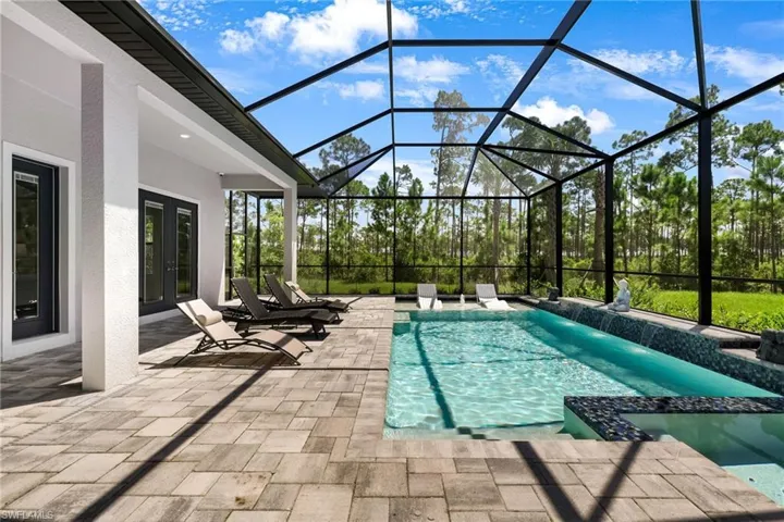 View of swimming pool featuring glass enclosure and a patio area