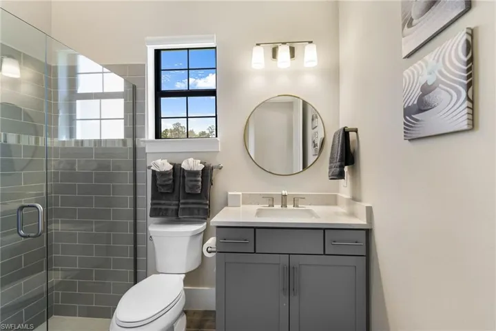 Bathroom featuring a shower with door, vanity, and toilet