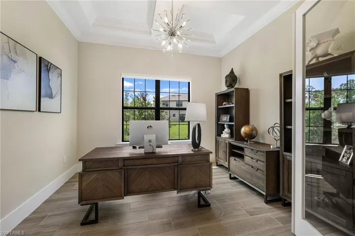 Home office with a notable chandelier, a tray ceiling, ornamental molding, and hardwood / wood-style flooring